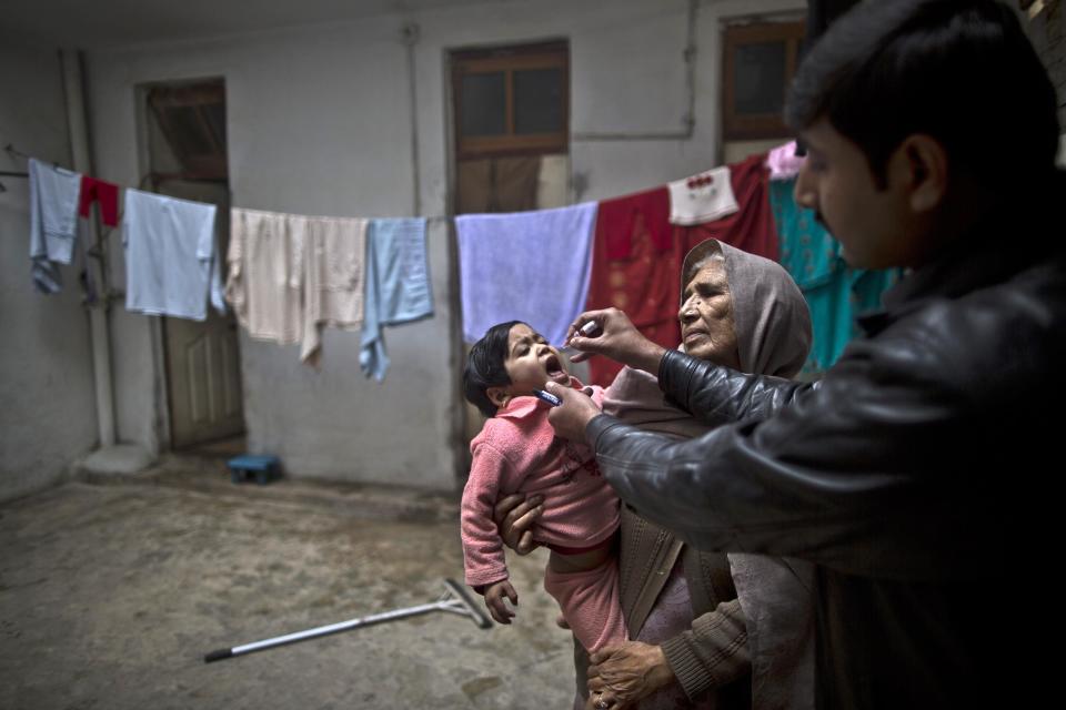 A Pakistani health worker, right, gives a polio vaccine to a child held by her grandmother at their home in Rawalpindi, Pakistan, Monday, Jan. 20, 2014. The World Health Organization said the northwestern Pakistani city of Peshawar has become the largest poliovirus reservoir in the world. (AP Photo/Muhammed Muheisen)