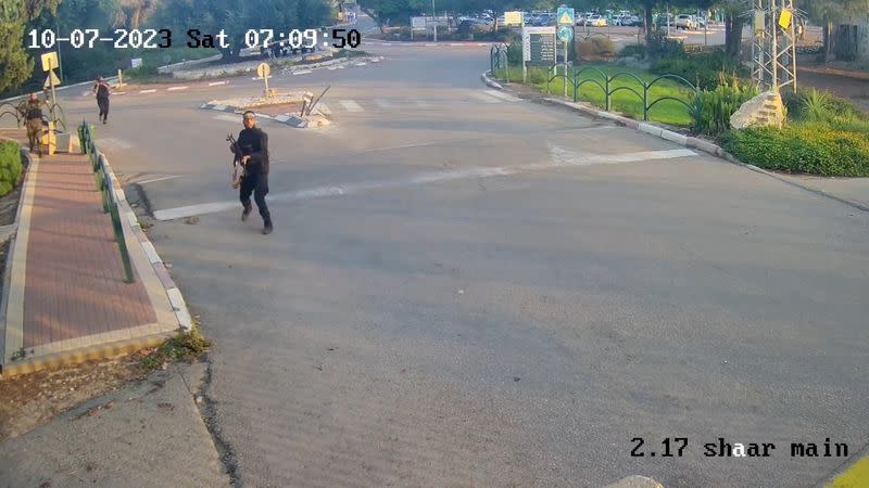 An armed man runs aiming his gun during the October 7 attack by Hamas in Kibbutz Alumim