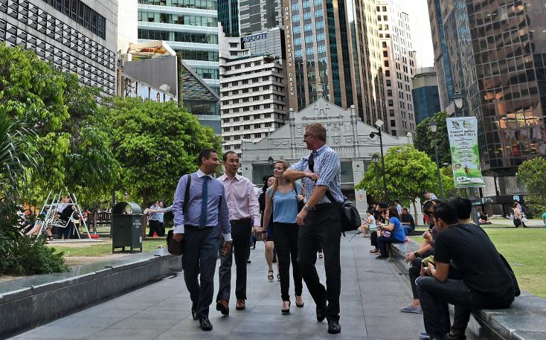 People walk along the pavement at Raffles Place financial district in Singapore