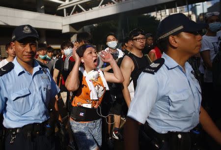 A woman shouts to a police officer as demonstrators block the main street to the financial Central district, outside the government headquarters in Hong Kong, September 29, 2014. REUTERS/Carlos Barria