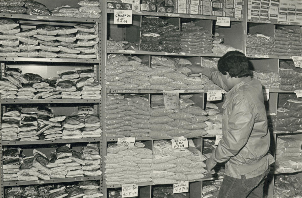 Owner's son stocking shelves in Patel Brothers store at 2542 West Devon Avenue in Chicago, November 1984. (Mukul Roy / Chicago History Museum)
