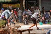 Protesters cover with makeshift shields during an anti-coup protest in Mandalay, Myanmar