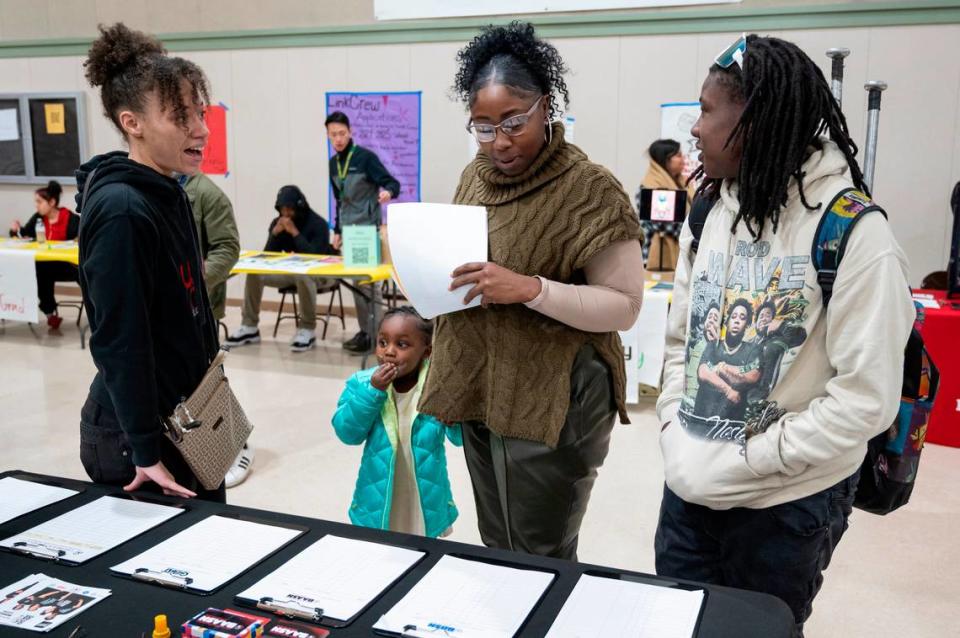 Kima Lee, left, program coordinator for the Black Youth Leadership Project, talks with Ebony Moss, center, as she gets information for her children Derreon, 15, and Arie, 4, at an open house at Monterey Trail High School in Elk Grove on Thursday, Jan. 11, 2023.