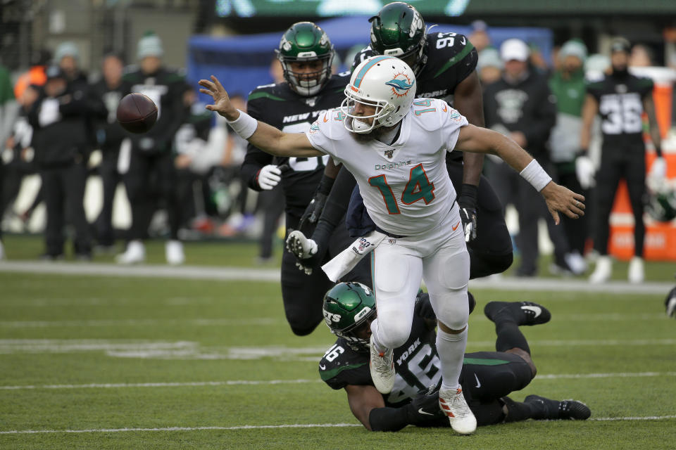 Miami Dolphins quarterback Ryan Fitzpatrick (14) flips a horizontal pass as he is tackled by New York Jets linebacker Neville Hewitt (46) during the second quarter of an NFL football game, Sunday, Dec. 8, 2019, in East Rutherford, N.J. (AP Photo/Seth Wenig)