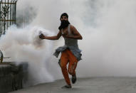 <p>A Kashmiri protester holds a tear smoke shell and chases government forces as he reacts to the Sunday’s killing of a young man in Srinagar, Indian controlled Kashmir, Monday, Aug. 22, 2016. A security lockdown and protest strikes continued for the 45th straight day Monday, with tens of thousands of Indian armed police and paramilitary soldiers in full riot gear patrolling the tense region. The killing of a popular rebel commander on July 8 sparked some of Kashmir’s largest protests against Indian rule in recent years. (AP Photo/Mukhtar Khan) </p>
