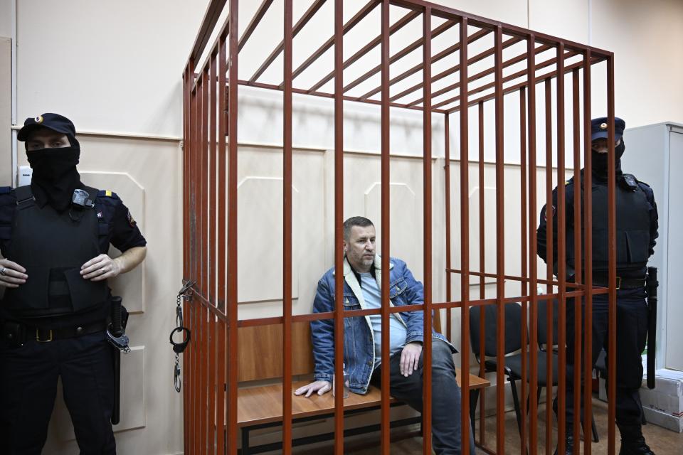 Opposition leader Alexei Navalny's lawyer Igor Sergunin, center, sits in a cage in a courtroom in Moscow, Russia, Friday, Oct. 13, 2023. Russian authorities on Friday detained three lawyers representing imprisoned opposition leader Alexei Navalny after searching their homes, his allies said, a step that comes amid increasing pressure on the Kremlin's critics. (AP Photo/Dmitry Serebryakov)