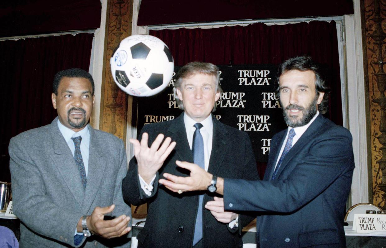 Donald Trump is flanked by soccer players Luis Pereira, left, of Brazil, and Julio Villa of Argentina, during a news conference in New York, on Jan. 29, 1992. Argentina and Brazil will meet in an exhibition Futbol 5 match at Trump Plaza Hotel and Casino in Atlantic City, N.J., March 28, 1992.