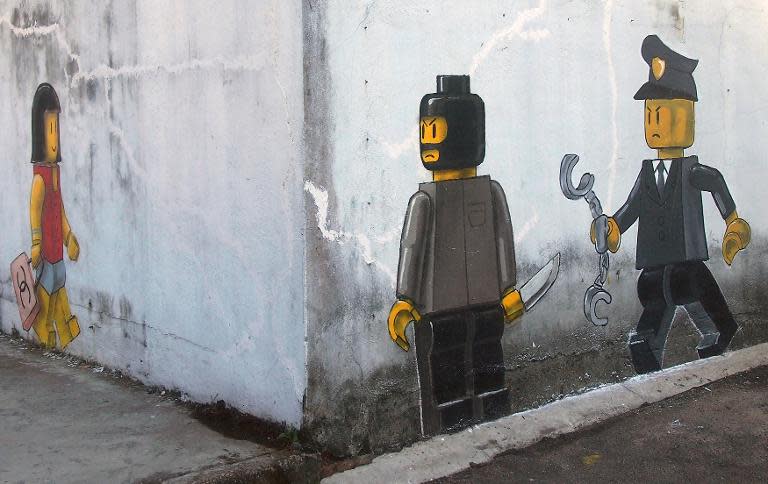 A mural by Lithuanian artist Ernest Zacharevic, which shows a Lego woman with a Chanel bag (L), a Lego robber armed with a knife (2nd, R) and a Malaysian authority member (R) is pictured in Johor Bahru on November 13, 2013