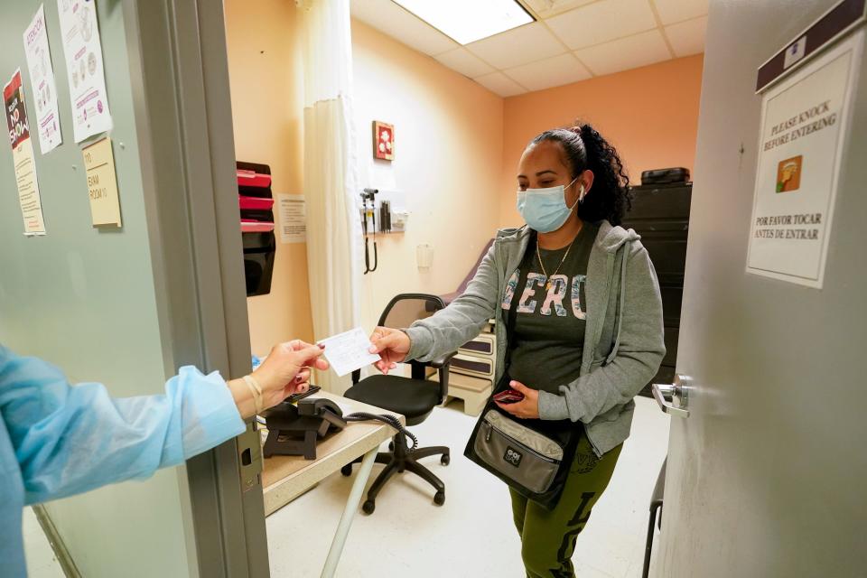 Registered nurse Anna Yadgaro, not pictured, hands Geidy Chirinos a vaccination card after inoculating her with the second dose of Moderna's COVID-19 vaccine at the Joseph P. Addabbo Family Health Center in New York.