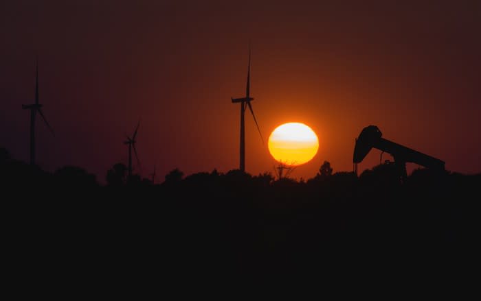 Wind turbines and oil pumpjack at sunset.