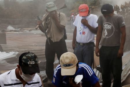 Residents cover their noses as they help find remains at the home of the father-in-law of Eufemia Garcia, 48, who lost 50 members of her family during the eruption of the Fuego volcano in San Miguel Los Lotes in Escuintla, Guatemala, June 12, 2018. REUTERS/Carlos Jasso