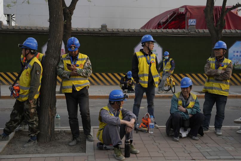 Workers wait for their ride outside a construction site in Beijing, April 2024