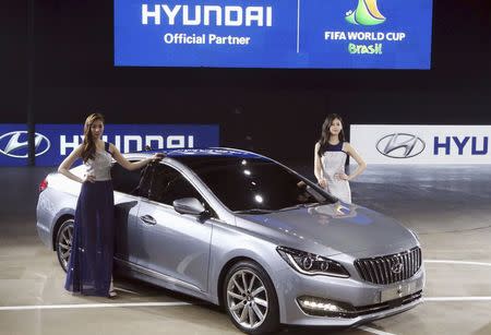 Models pose for photographs with Hyundai Motor Co's New sedan The AG at Busan International Motor Show 2014 in Busan May 29, 2014. REUTERS/Jo Jung-ho/Yonhap