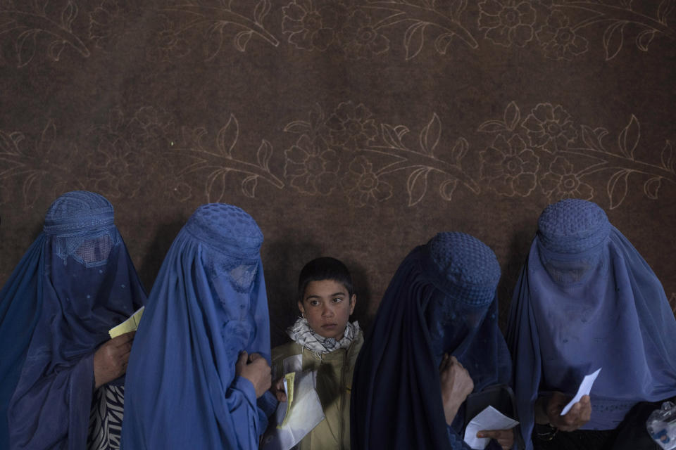 FILE - Afghan women wait to receive cash at a money distribution point organized by the World Food Program, in Kabul, Afghanistan, on Nov. 20, 2021. (AP Photo/Petros Giannakouris, File)