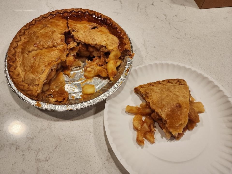 Whole apple pie with a slice of pie on a white plate next to it