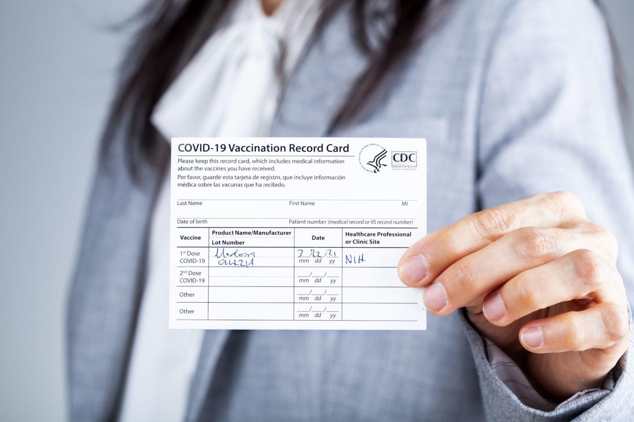 Clarksburg, MD, USA 03-29-2021: A caucasian businesswoman is showing her CDC issued COVID vaccination record card as a proof of immunization. It has the date and lot number on it.