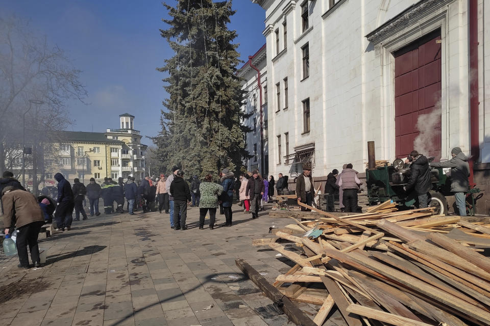 Residents of Mariupol, Ukraine, wait for food at the field kitchen outside of the Donetsk Academic Regional Drama Theatre on March 9, 2022, in Mariupol. The March 16, 2022, bombing of the theater stands out as the single deadliest known attack against civilians to date in the Ukraine war. (Lev Sandalov via AP)