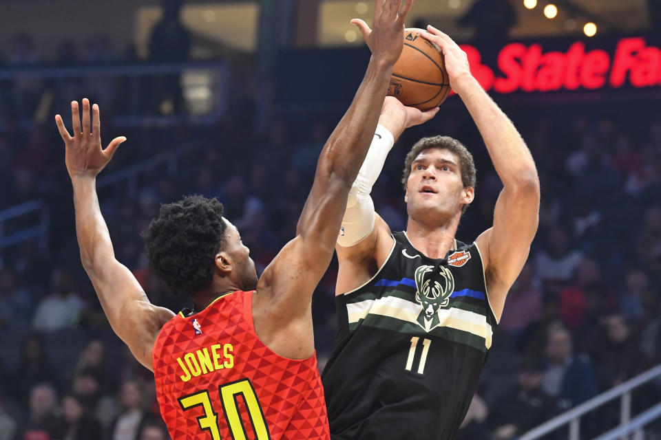 Milwaukee Bucks center Brook Lopez (11) shoots as Atlanta Hawks center Damian Jones defends during the first half of an NBA basketball game Friday, Dec. 27, 2019, in Atlanta. (AP Photo/John Amis)