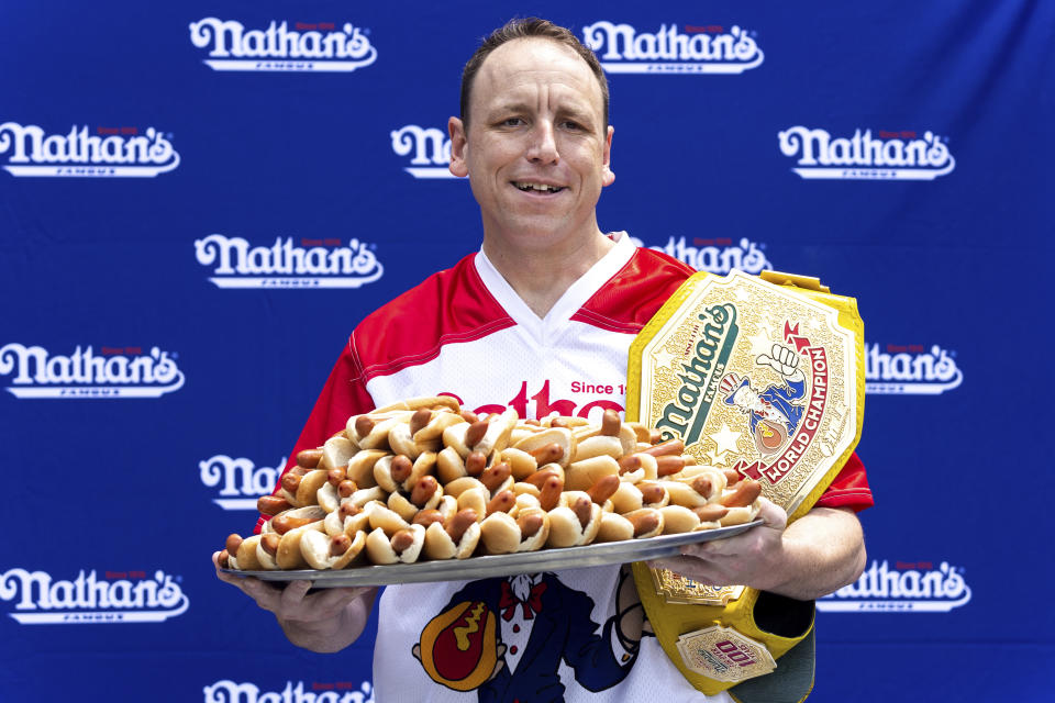 Competitive eater Joey Chestnut poses for photos with 76 hot dogs at a weigh-in before the Nathan's Famous July Fourth hot dog eating contest, Friday, July 1, 2022, in New York. Chestnut is seeking to set a new world record this year.(AP Photo/Julia Nikhinson)