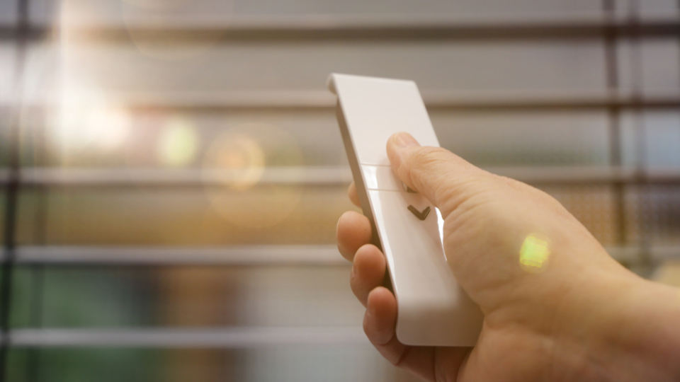 The best smart blinds: Image depicts woman controlling blinds via remote