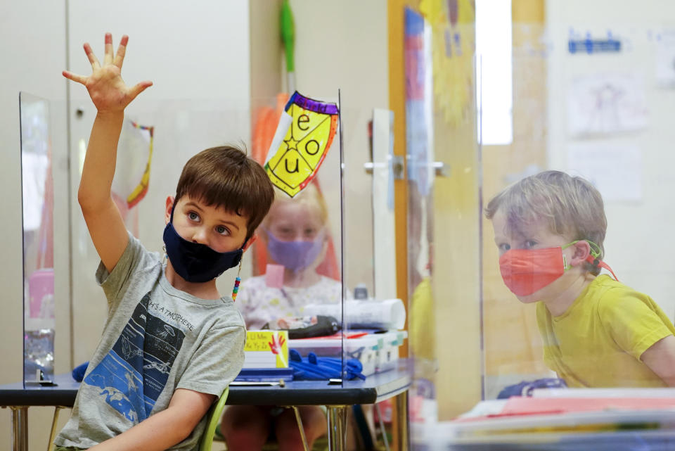 FILE - In this May 18, 2021, file photo, kindergarten students wear masks and are separated by plexiglass during a math lesson at the Milton Elementary School, in Rye, N.Y. School districts across the United States are hiring additional teachers in anticipation of what will be one of the largest kindergarten classes ever as enrollment rebounds following the pandemic. (AP Photo/Mary Altaffer, File)