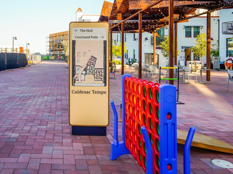 Culdesac, Tempe: A red, brick courtyard with a map in the middle and jumbo Connect Four and shaded tables on the left