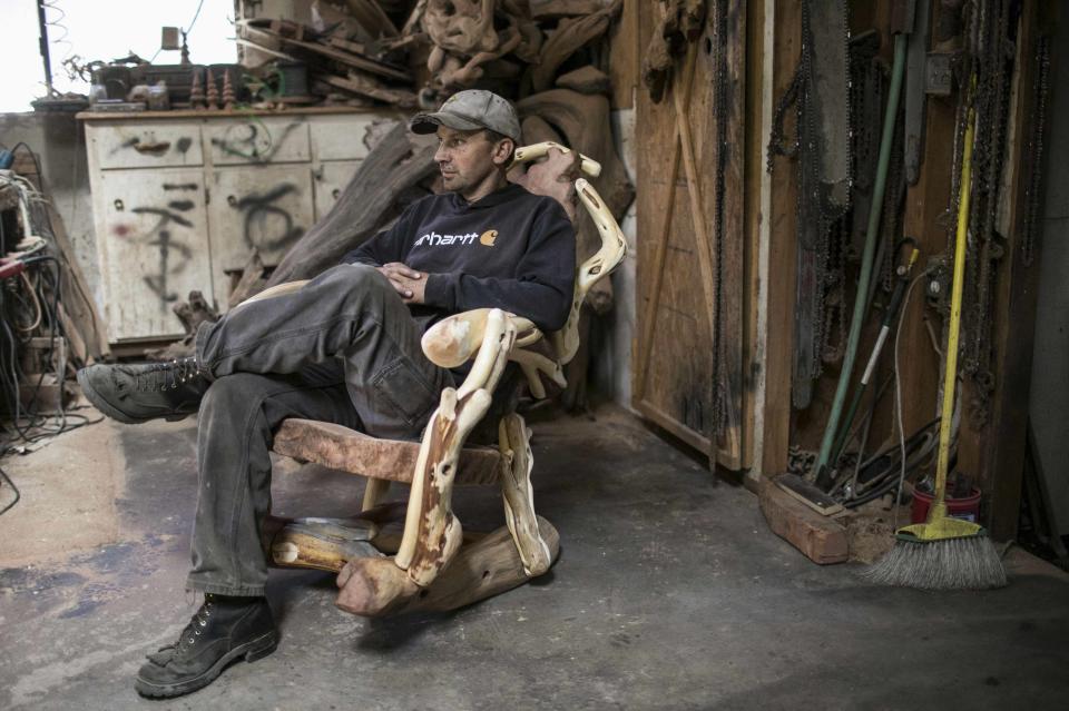 Tim Duncan sits in the redwood burl rocking chair he crafted at his shop in Orick, California June 3, 2014. Duncan sells most of his rustic furniture and carvings outside of the small Northern California town. Picture taken June 3, 2014. REUTERS/Nick Adams (UNITED STATES - Tags: BUSINESS)