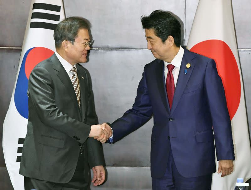 Japan's Prime Minister Shinzo Abe shakes hands with South Korea's President Moon Jae-in during their meeting in Chengdu, China