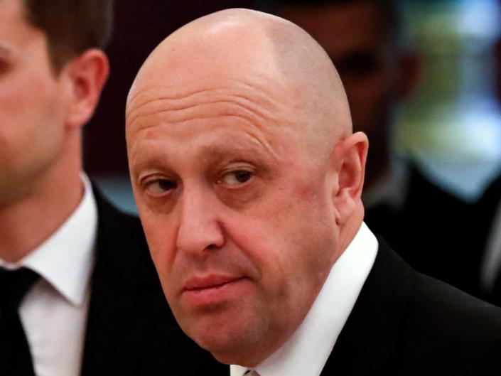 Yevgeny Prigozhin sitting at a table with other people while wearing a black suit and a silver tie at a formal event.