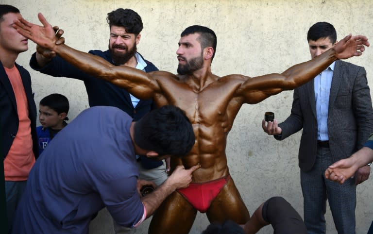 Bodybuilder Hares Mohammadi, 25, being covered in fake tan during a contest in Kabul