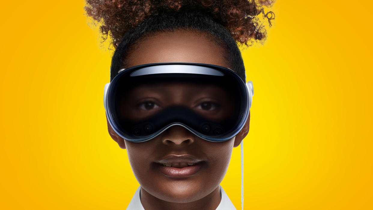  A woman wearing an Apple Vision Pro headset on an orange background. 