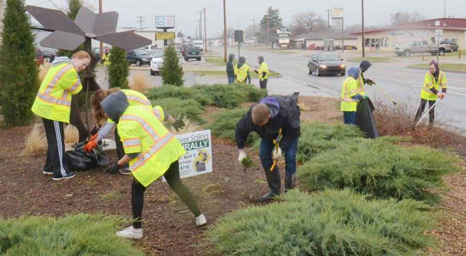 Members of First Covenant Church's youth group and other volunteers work together Saturday to pull weeds and pick up trash at the 5 Corners intersection of Broadway Blvd and Pacific Ave.  during an earlier Spring Spruce-up.
