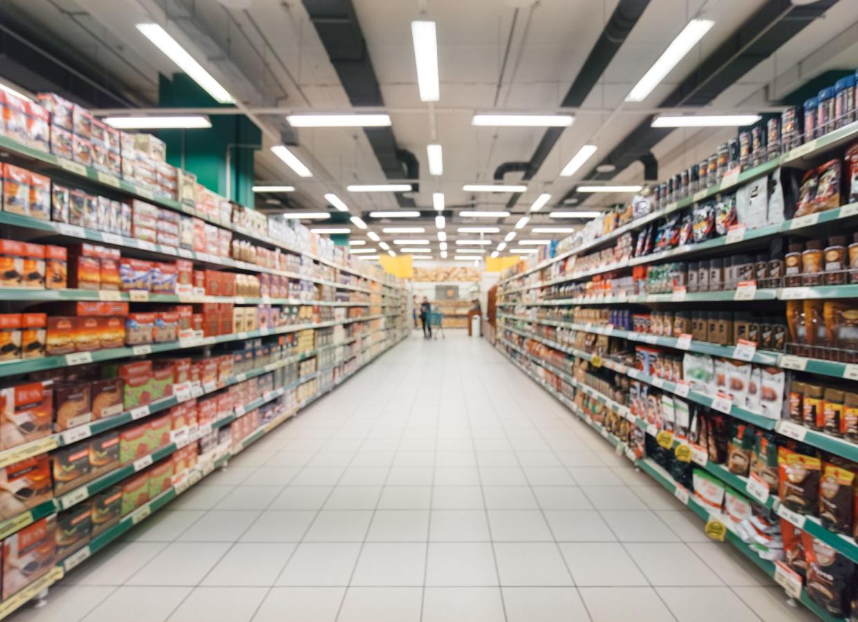 Abstract blurred supermarket aisle with colorful shelves and unrecognizable customers as background