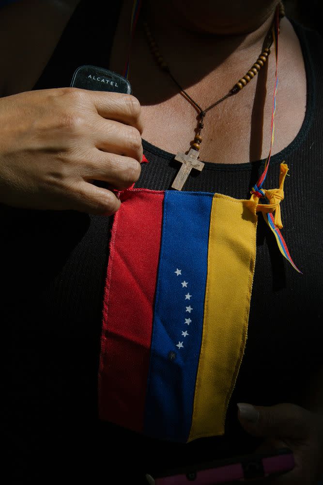 A woman fixes a flag on her chest during a news conference by Guaidó at the Bolivar Square of Chacao in Caracas on Jan. 25, 2019.