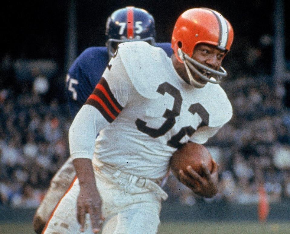 Jim Brown carries the ball against the New York Giants, Nov. 14, 1965, in Cleveland. The No. 6 overall pick in 1957. Brown rushed for 12,312 yards in nine seasons for the Browns, leading the NFL in eight seasons. The three-time MVP walked away from his career at its peak to pursue acting.