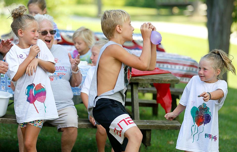 Donna Messerly (seated in rear) reacts as Lincoln Garver catches a water balloon and his sisters Kennedy (left) and Raegan participate in a water balloon game during messy camp at Charles Mill Lake. Messerly, 81, is the camp director.