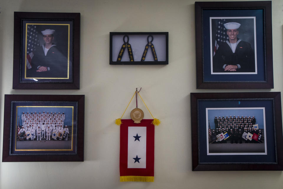 Robert Decker displays photographs to honor the U.S. Navy service of both of his sons, Kyle and Kody, at his home in Norfolk, Va., on Tuesday, March 14, 2023. Decker's youngest son, Kody, committed suicide in October 2022 while stationed at Norfolk Naval Station. (AP Photo/John C. Clark)