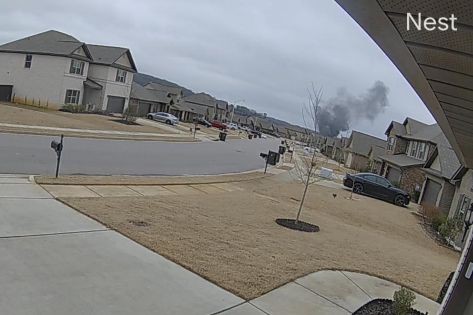 In this image made from video taken from a Nest camera provided by Mia McShan, a cloud of black smoke rises from where a Black Hawk helicopter crashed on Wednesday, Feb. 15, 2023, in Alabama. U.S. military officials say two people on board were killed. (Mia McShan via AP)