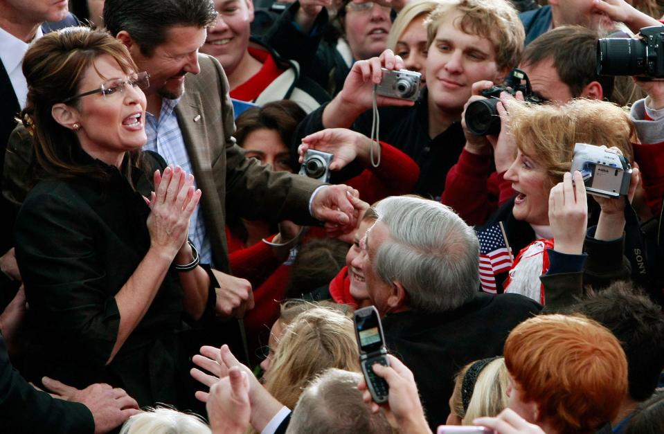 2008 GOP vice presidential nominee Sarah Palin and her husband Todd are surrounded by supporters holding up digital cameras and flip phones while campaigning in Leesburg, Virginia.