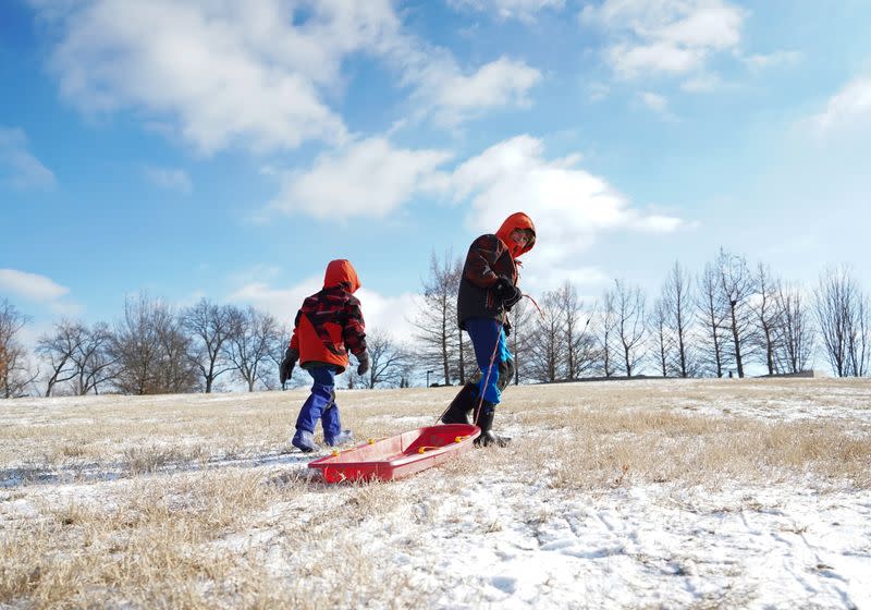 Two kids climb Art Hill at Forest Park with their sled during cold weather in St Louis