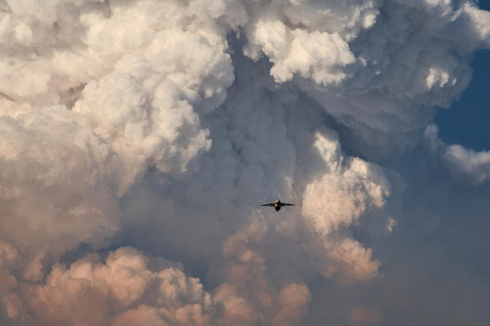 A firefighting aircraft returns to base amid massive plumes of smoke after dropping flame-retarding chemicals on the Bootleg Fire in Bly, Oregon, on July 15.