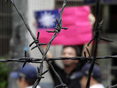 A pro-democracy activist holds up Taiwan's national flag in front of police officers while Zhang Zhijun (unseen), director of China's Taiwan Affairs Office, visits the labour activity centre in New Taipei City, in this June 26, 2014 file photo. REUTERS/Pichi Chuang/Files