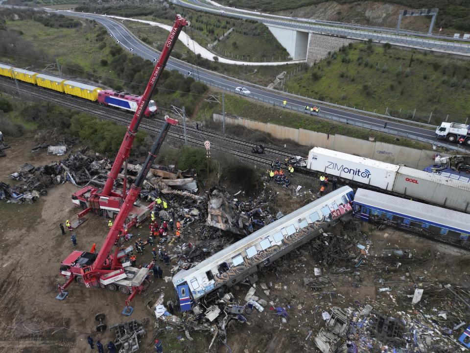 Firefighters and rescuers supported by two cranes, search through the wreckage after a trains collision in Tempe, about 376 kilometres (235 miles) north of Athens, near Larissa city, Greece, Thursday, March 2, 2023. Emergency workers are searching for survivors and bodies after a passenger train and a freight train crashed head-on in Tempe, central Greece just before midnight Tuesday. It was the country's deadliest rail crash on record. (AP Photo/Vaggelis Kousioras)