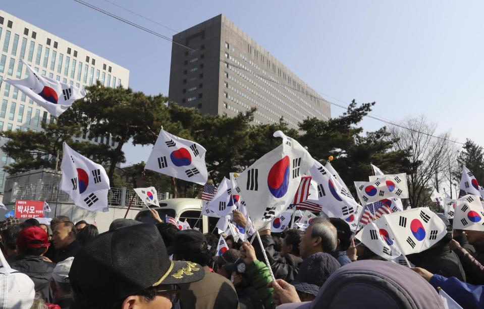 Supporters of South Korean ousted President Park Geun-hye hold flags outside of a prosecutors' office in Seoul, South Korea, Tuesday, March 21, 2017. Park said she was "sorry" to the people as she arrived Tuesday at a prosecutors' office for questioning over a corruption scandal that led to her removal from office. (AP Photo/Lee Jin-man)