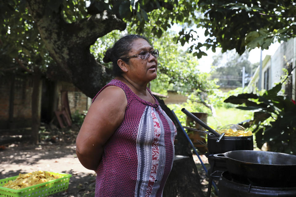 In this Oct. 10, 2019 photo, María Teresa Carballo stands outside of her house in Santa Ana, El Salvador. Like much of Central America’s massive migration of recent years, the driving force behind the Carballo family’s exodus has been fear. Carballo lives in a neighborhood controlled by one gang, but every morning at 5 a.m. she travels to the city’s central market, which is controlled by another gang, to buy yucca, plantains and potatoes to make the fried chips she sells for a living. (AP Photo/Eduardo Verdugo)