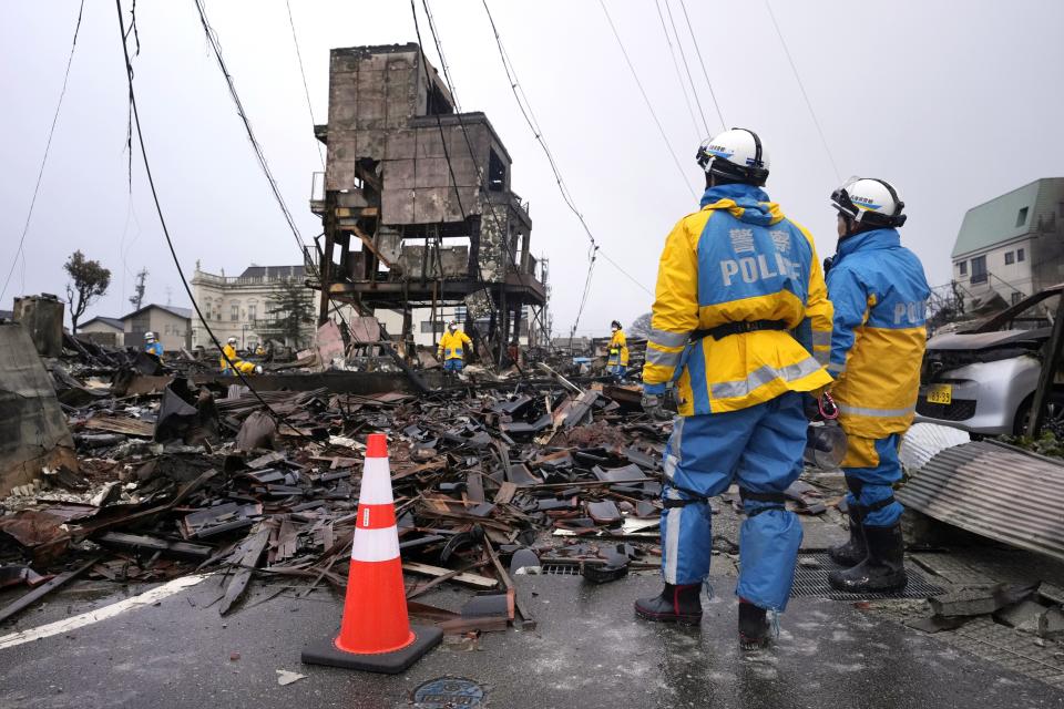 Police officers search victims from debris of damaged and burnt buildings in Wajima in the Noto peninsula facing the Sea of Japan, northwest of Tokyo, Sunday, Jan. 7, 2024. Monday's temblor decimated houses, twisted and scarred roads and scattered boats like toys in the waters, and prompted tsunami warnings. (AP Photo/Hiro Komae)