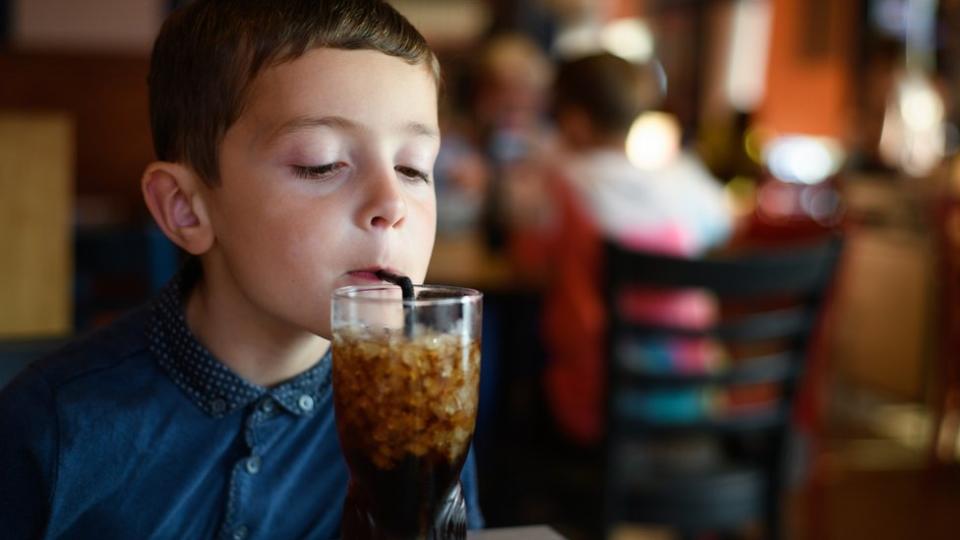Um menino tomando bebida de cola