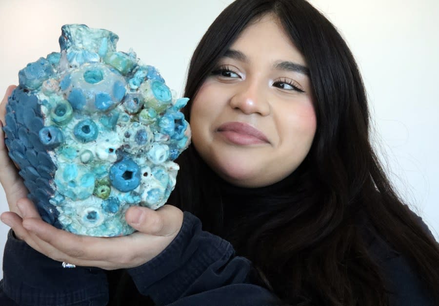 Alyssa Mancilla, a senior at Ysleta High School, holds her ceramic vase made of fired red clay Thursday at the EPCC Salute to the Arts Student Portfolio Day.