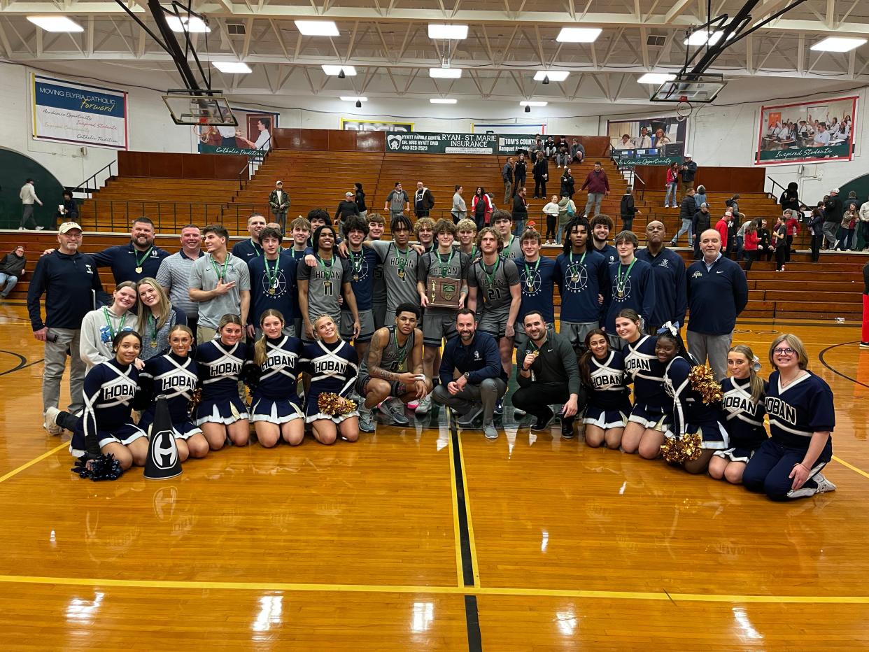 Archbishop Hoban boys basketball coaches and players join cheerleaders and team managers for a photo after winning a Division I district championship against Brecksville at the Elyria Catholic Coliseum on March 9, 2024.