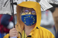 A member of a pro-European German association holds an umbrella on a footbridge over the Rhine river that links France to Germany, Sunday June 14, 2020 in Strasbourg, eastern France. The majority of European countries will be reopening Monday June 15, 2020 their borders and lifting the restrictions that had been in place during the COVID-19 pandemic. (AP Photo/Jean-Francois Badias)